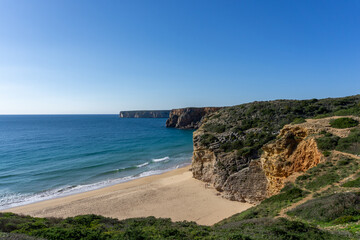 Fototapeta na wymiar golden sand beach with wild tall cliffs and ocean