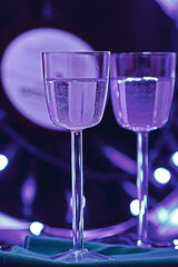 selective focus photo of two glasses of champagne on the background of a vinyl record, surrounded by bright club illumination