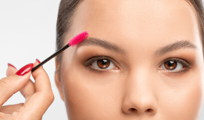 Makeup artist combs  and plucks eyebrows after dyeing in a beauty salon.Professional makeup and...