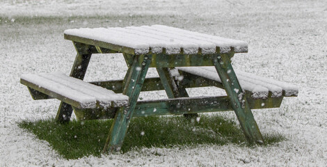 Picnic table under a fall of snow in a snowstorm