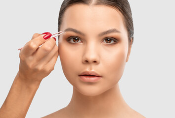 Makeup artist combs  and plucks eyebrows after dyeing in a beauty salon.Professional makeup and...