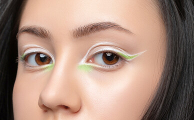 Portrait of a beautiful teenage girl with dark hair, with beautiful creative white and green makeup...
