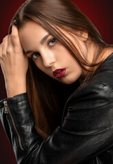 Fototapeta premium Brunette girl with beautiful makeup, with clean skin, long hair in a black leather jacket. makeup concept