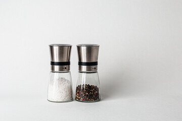 Salt and pepper grinders. Dried whole seed of black pepper and white coarse sea salt isolated on a...