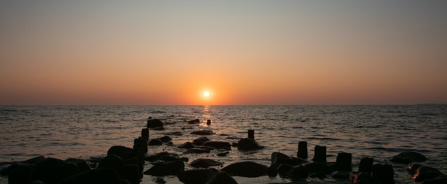 Scenic seascape with groyne at sunrise.
