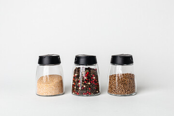 Salt and pepper grinders. Dried whole seed of black pepper and white coarse sea salt isolated on a...