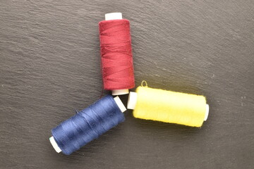 Several spools of colored thread, close-up, on a slate board.