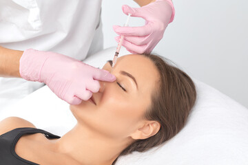 Cosmetologist makes rejuvenating anti wrinkle injections on the face of a beautiful woman. Female...