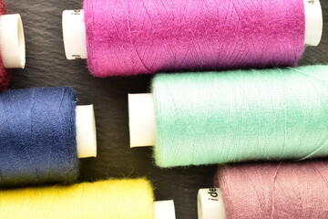 Several spools of colored thread, close-up, on a slate board.