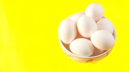 Organic white chicken eggs isolated on yellow background.