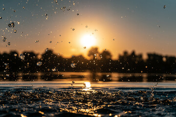 closeup of girl hand silhouette play or splash water in lake on beach at sunset