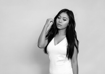 Naklejka premium Beautiful young woman with long black hair posing in dress on grey background