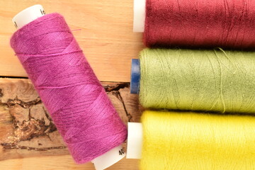 Several spools of colored thread, close-up, on a wooden table.