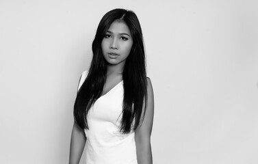 Fototapeta premium Beautiful asian woman with long black hair posing in dress on grey background