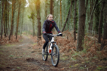 Fototapeta na wymiar beautiful young woman mountain biking in the forest in winter