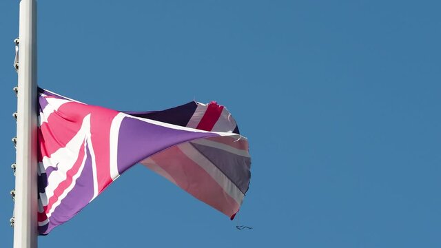 Great Britain flag fluttering in the wind. National flag against a blue sky, high flagpole