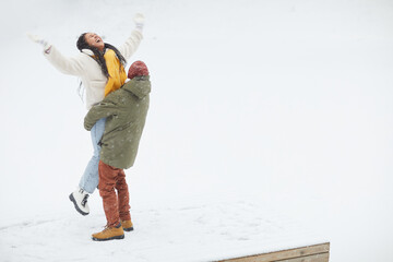 Happy woman happy with winter and snow together with man who holding her in his hands