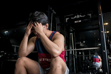 A frustrated young man holds his hands up to his forehead. Concept of workout plateau at the gym.