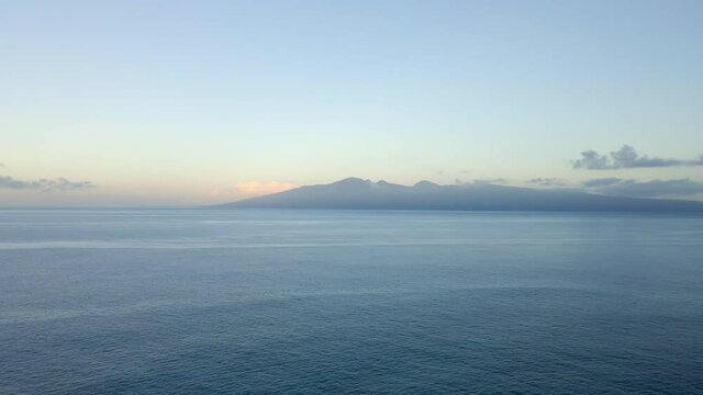 Vast Pacific Ocean ripple wave and silhouette of tropical island
