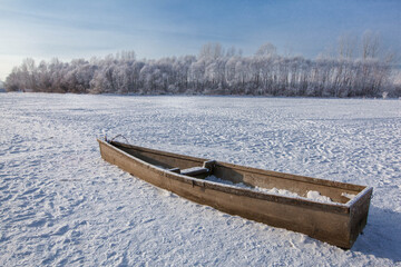 Old boat on the lake covered with snow in winter