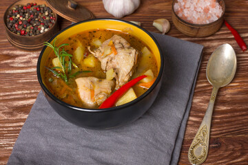 Deep plate with stewed potatoes and chicken meat on a wooden table