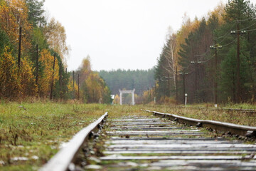 beautiful autumn view of abandoned railway in russian outback with bridge on the background
