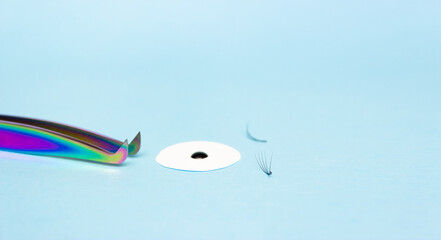 Eyelash extension tweezers, glue, blue background. Tools for the lashmaker.