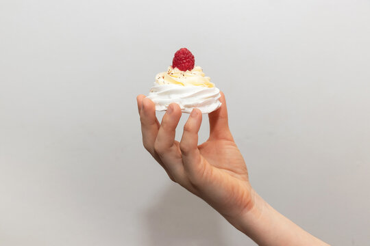 A Woman's Hand Holding A Pavlova Cake On A Light Background