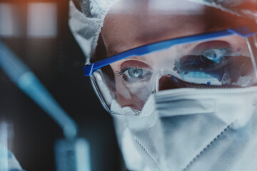 Laboratory technician wearing safety mask and goggles, pipetting out compounds to testing tube....