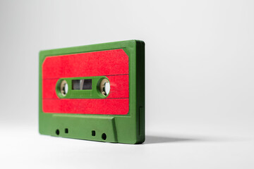 Obraz premium Close-up of green-red vintage music cassette on white background.