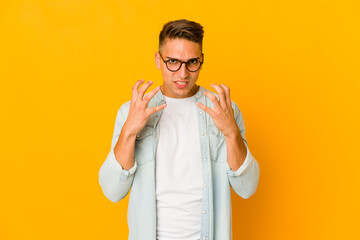 Young handsome caucasian man isolated upset screaming with tense hands.