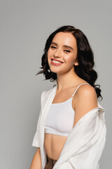  brunette woman in white shirt and top looking at camera isolated on grey