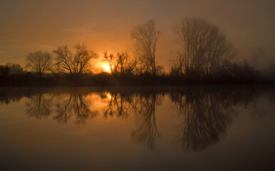 Obraz premium Spiegelung eines idyllischen Sonnenaufgangs an einem nebligen Morgen