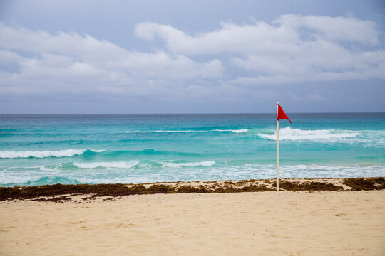 Red flag on the beach and waves in cancun Mexico