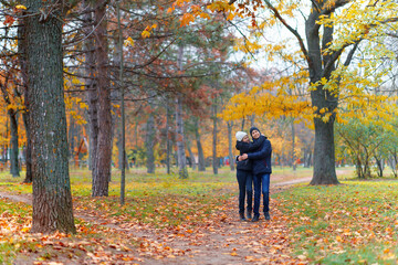 teen girl and boy walking through the park and enjoys autumn, beautiful nature with yellow leaves