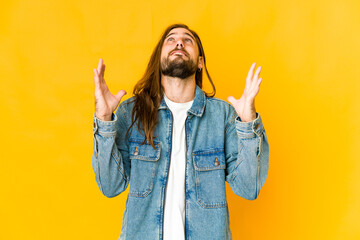 Young man with long hair look laughs out loudly keeping hand on chest.