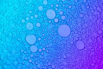 Mixture of oil and water on blue and purple Background, macro shot
