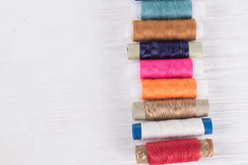 various sewing threads on a white wooden background