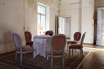 Small bouquet of flowers in a ceramic jug on a round table in the room of an old house