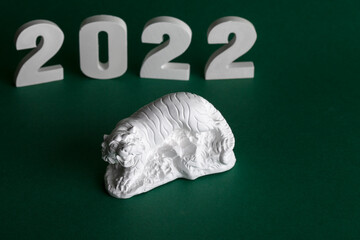 2022 year of the tiger. Tiger white tiger figurine - symbol of 2022 on a green background