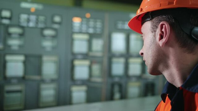 Engineer wearing an orange protective mask, hand finger press button controling cnc machine, workers operating factory machinery in warehouse machinery factory. Close up