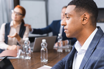 Side view of african american businessman near blurred colleagues on background in boardroom.