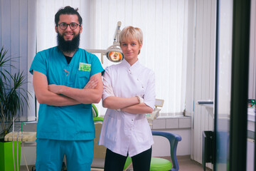 Obraz premium Smiling bearded dentist standing with his beautiful young female colleague in their dental office