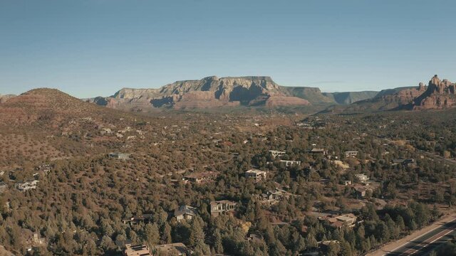 Aerial Drone View of residential areas and roads in Sedona and Oak Creek Canyon in Arizona on a bright and sunny fall day showing unique red rock formations and landscapes 