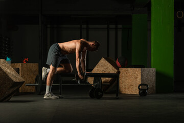 Fototapeta na wymiar Athletic caucasian man doing a dumbbell triceps kickback with his right arm on a horizontal bench.