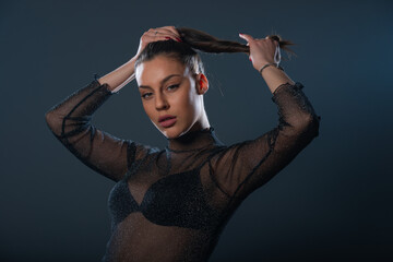 Fashion portrait of an attractive brunette girl holding and pulling her ponytail.