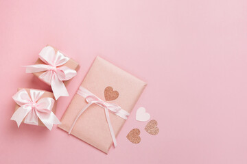 Gift boxes with pink ribbon and hearts on pastel pink background. Valentines day composition with free space. Top view, flat lay.
