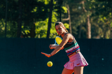 Young female tennis player hitting the ball to the ground with a racket while waiting for the...