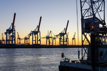 Fototapeta na wymiar Hamburg, Germany: Shipyard cranes at the docks in the port in the twilight