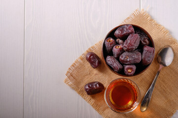 A cup with dates, a mug of tea and a teapot on a white table, a place for an inscription